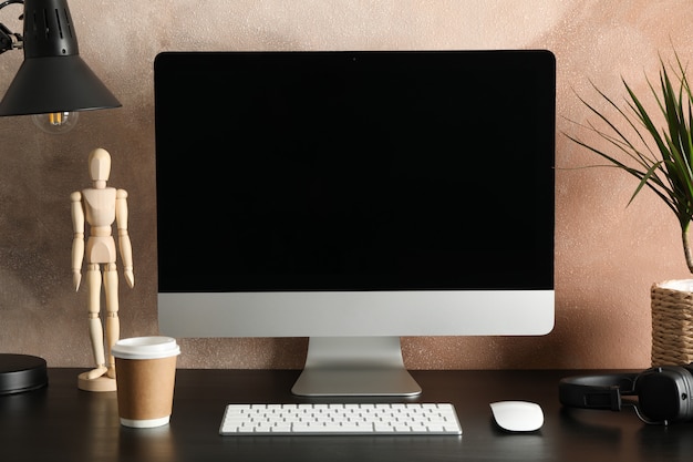 Computer, plant and wood man on wooden table. Workplace room