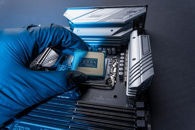 Premium Photo A computer processor in a gloved hand against the background of the motherboard Accessories and computer equipment Central processing chip or microprocessor