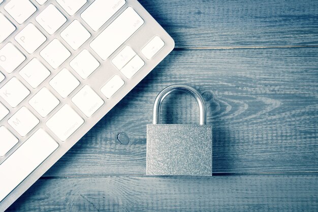 Computer security concept. unlocked padlock on laptop keyboard.\
safe symbol. selective focus on gray wooden table