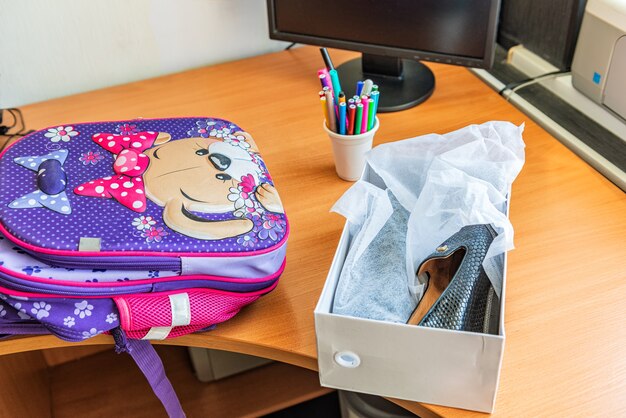 On the computer table are a school satchel and new shoes