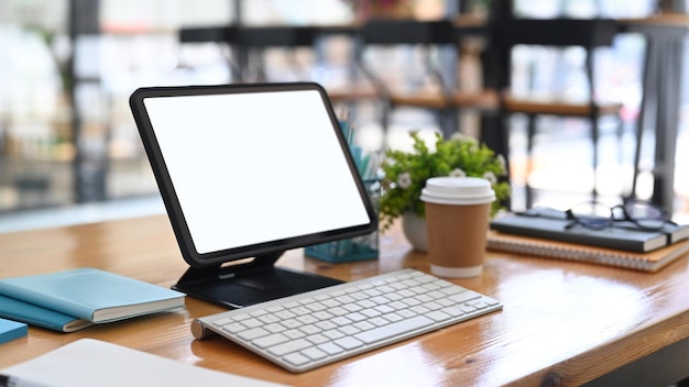 Computer tablet keyboard notebook and coffee cup on wooden table