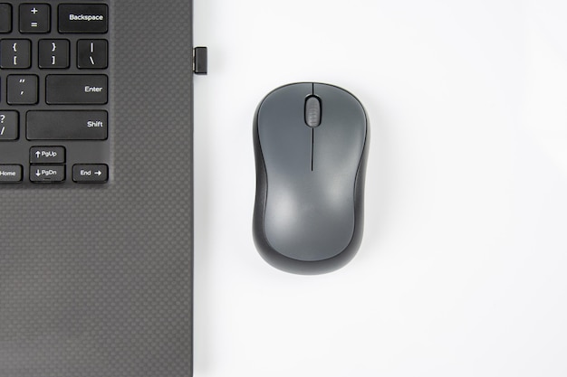 Mouse wireless per computer accanto a un computer portatile su un tavolo bianco primo piano industria elettronica personale