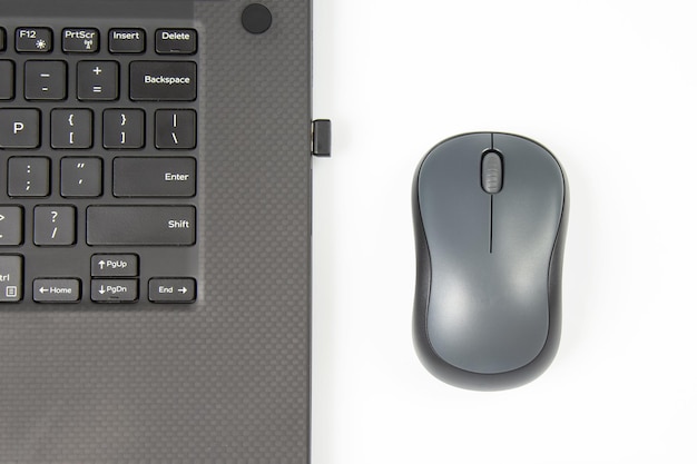 Computer wireless mouse next to a laptop on a white table closeup electronic personal industry