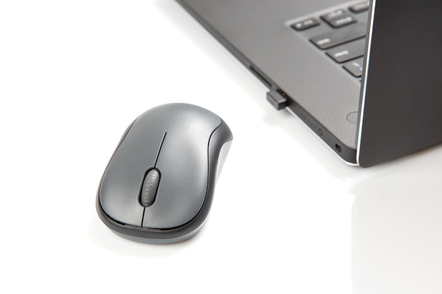 Mouse wireless per computer accanto a un computer portatile su un tavolo bianco primo piano industria elettronica personale