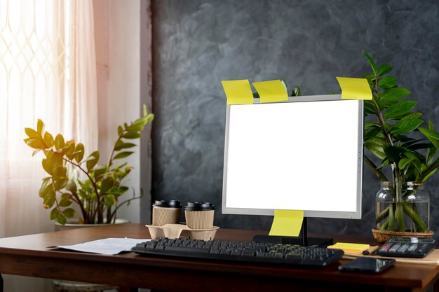 A computer with blank screen lamp plant organizer and glasses cup mouse three datebooks and pencils Front view Concept of work