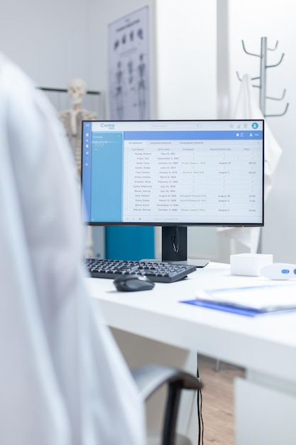 Computer with medical patients examination document on screen standing on table in empty doctors office. Hospital workplace having professional instruments ready for disease consultation