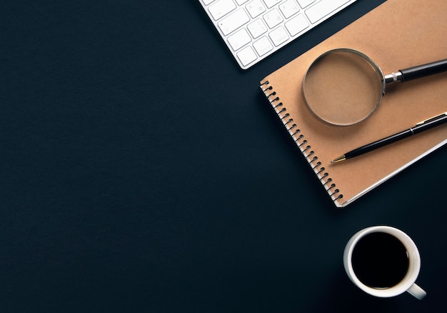 Computer with notepad and coffee on office black table