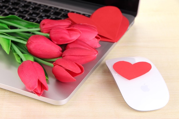 Computer with red hearts and flowers on table close up