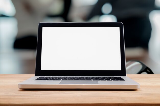 Computer with white screen on table with blur background.