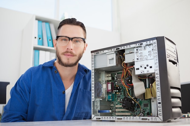 Computeringenieur die bij camera naast open console glimlachen