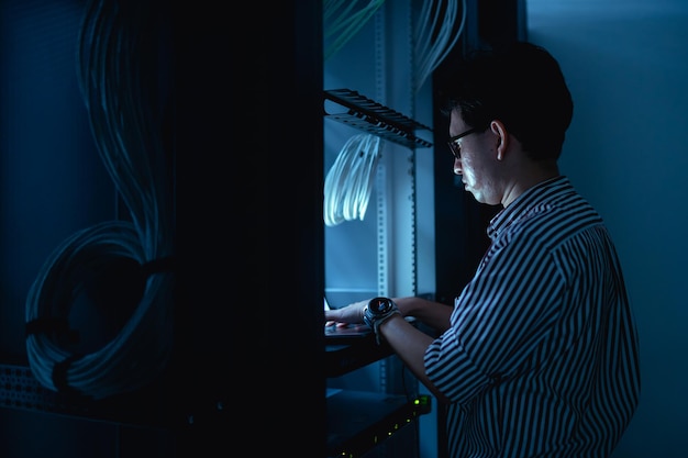 Foto computeringenieur stelt een netwerk op in de serverruimte system maintenance technician mannelijke ingenieur werkt in de serverkamer in een modern datacentrum