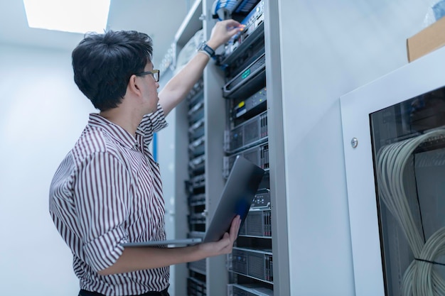 Computeringenieur stelt een netwerk op in de serverruimte System Maintenance Technician Mannelijke ingenieur werkt in de serverkamer in een modern datacentrum