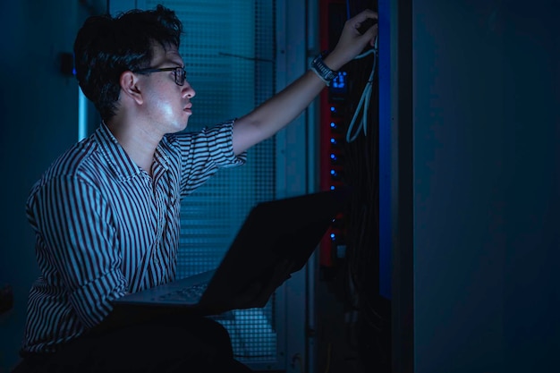 Computeringenieur stelt een netwerk op in de serverruimte System Maintenance Technician Mannelijke ingenieur werkt in de serverkamer in een modern datacentrum