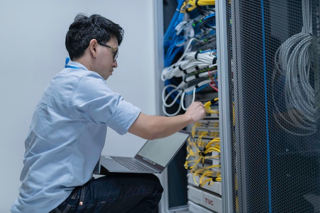 Computeringenieur stelt een netwerk op in de serverruimte System Maintenance Technician Mannelijke ingenieur werkt in de serverkamer in een modern datacentrum