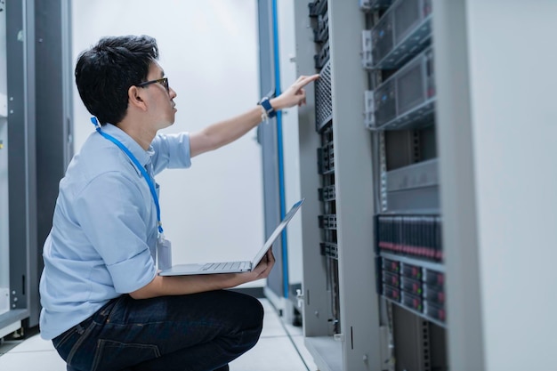 Computeringenieur stelt een netwerk op in de serverruimte System Maintenance Technician Mannelijke ingenieur werkt in de serverkamer in een modern datacentrum