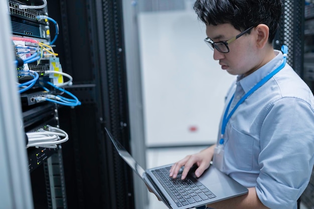 Computeringenieur stelt een netwerk op in de serverruimte System Maintenance Technician Mannelijke ingenieur werkt in de serverkamer in een modern datacentrum