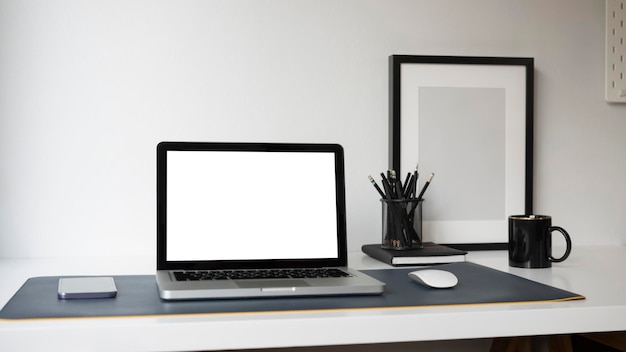 Computerlaptop met leeg scherm smartphone potloodhouder en leeg frame op thuiskantoor bureau