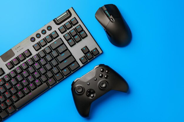 Computertoetsenbord en joystick op blauwe achtergrond bovenaanzicht