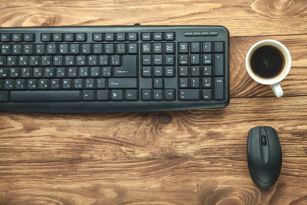 Computertoetsenbord en koffie op houten bureau.