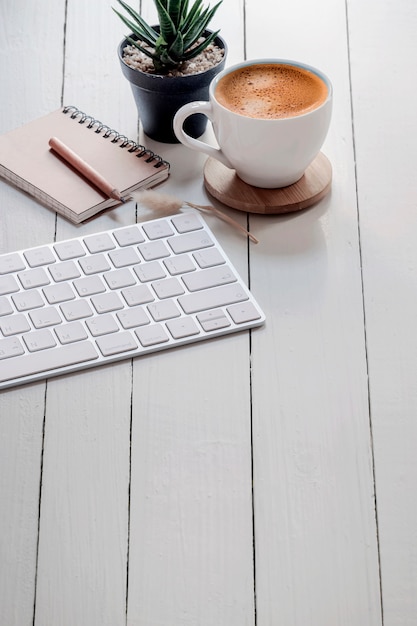 Computertoetsenbord en kop van koffie op witte houten lijst