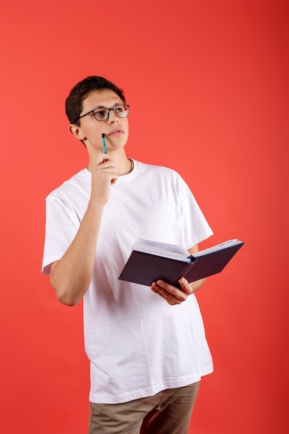 Conceived student in glasses holding a notebook and looking