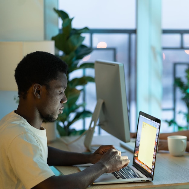 Concentrated African American man student typing email on laptop keyboard sits at office table desk