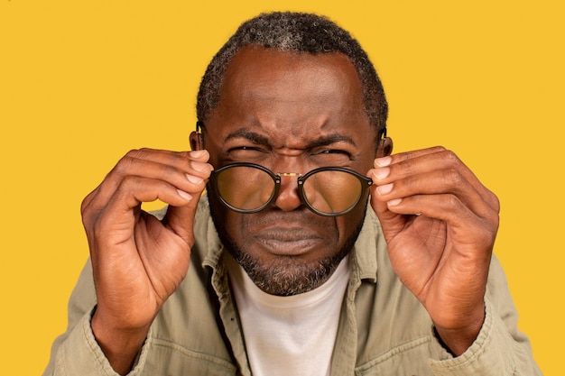 集中して目を細めるアフリカ系アメリカ人の中年男性が眼鏡を脱いでカメラを見る