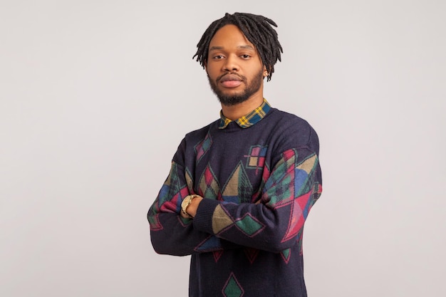 Photo concentrated african man with dreadlocks seriously and professionally looking at camera assertiveness indoor studio shot isolated on gray background
