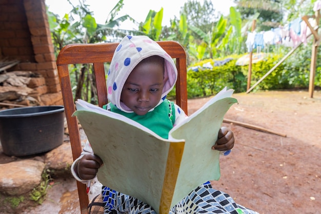 Concentrated African toddler studying sitting on a chair at home