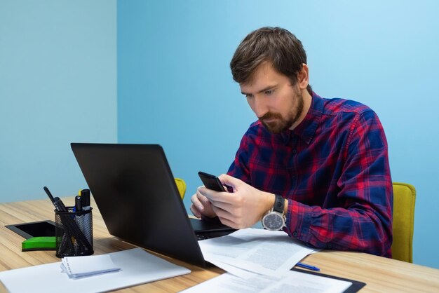 Concentrated bearded man working in the office sitting at the office table