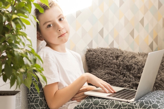 Photo concentrated boy sitting at desk with laptop and doing homework