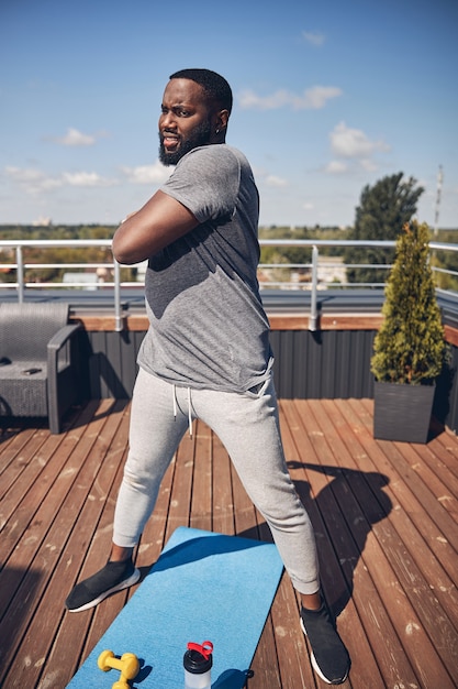 Concentrated brunette man doing sport on terrace