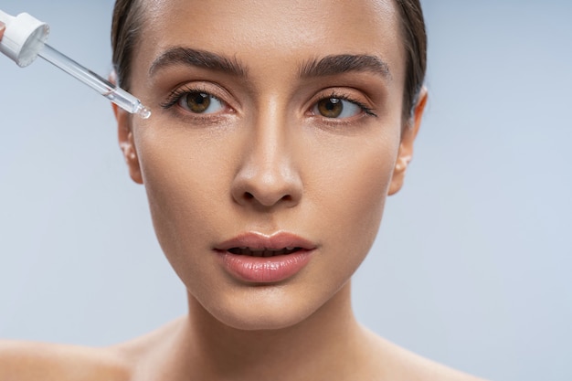 Concentrated brunette woman taking care of her skin