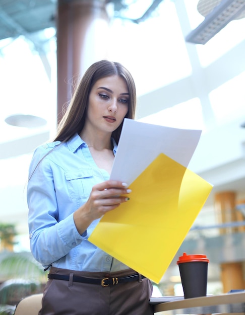 Signora d'affari concentrata che confronta i documenti in ufficio.