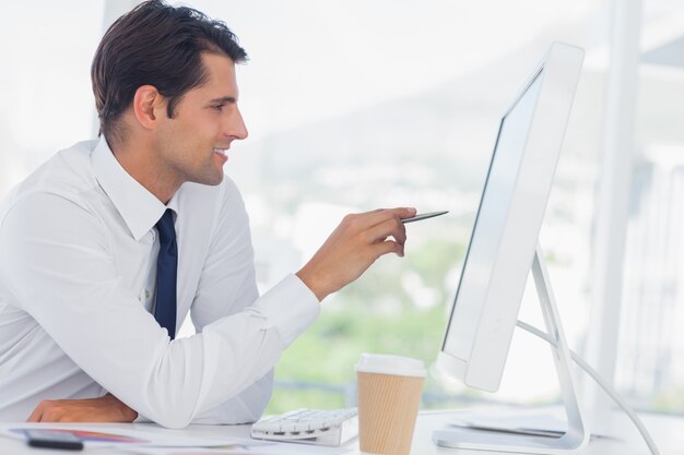 Concentrated businessman analyzing documents on his computer screen