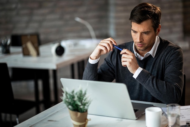 Concentrated businessman reading something on a computer while working in the office