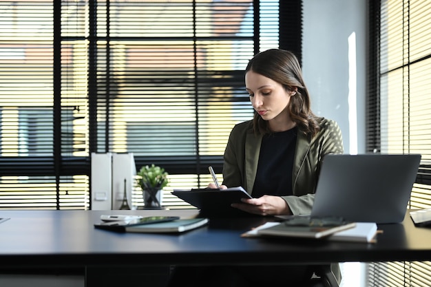 Concentrated caucasian female economist analyzing financial market on laptop computer at work station