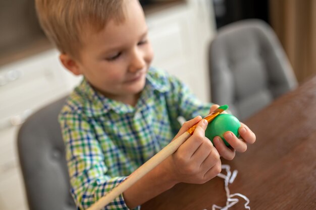 Bambino dipinto concentrato sulla superficie di un guscio d'uovo