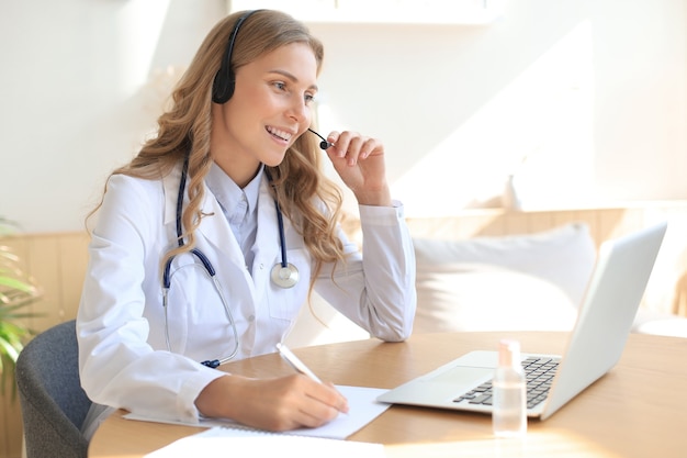 Concentrated doctor working online with a laptop sitting in a desk in a consultation.