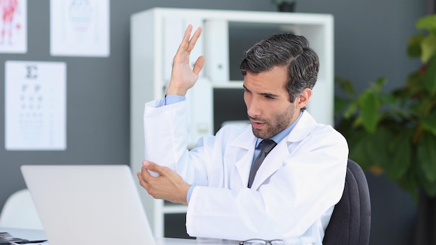 Concentrated doctor working with laptop at desk in office