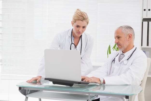노트북을 사용하는 집중된 의사 동료