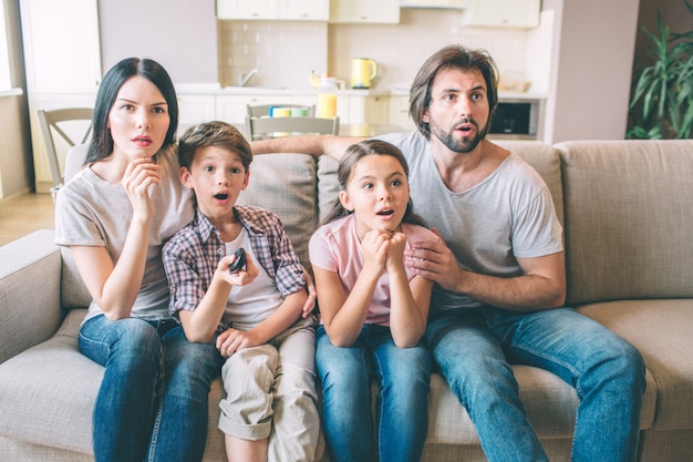 Concentrated family is sitting on sofa and watching