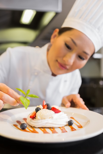 Chef femminile concentrato che guarnisce alimento