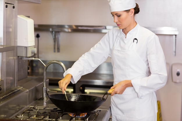 Concentrated female chef preparing food in kitchen