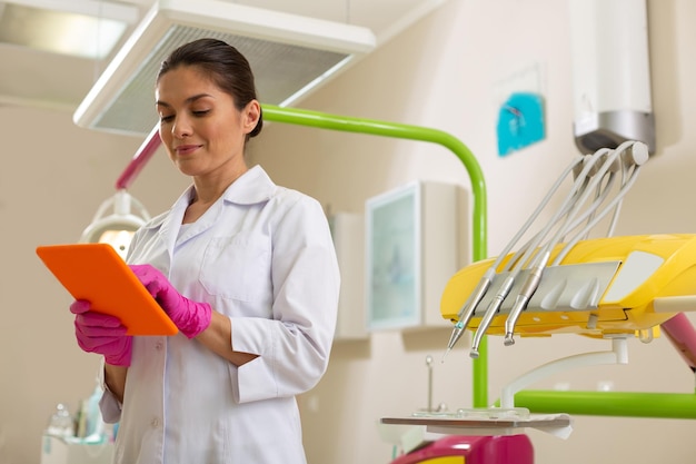 Photo concentrated female dentist standing with an orange tablet