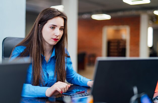 집중된 여성 개발자가 현대 사무실에서 컴퓨터 작업을 하고 있습니다. 매력적인 젊은 여성 프로그래머가 IT 회사에서 새로운 기술을 개발하고 있습니다. 고품질 이미지