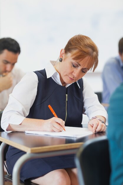 Foto studente maturo femminile concentrato che si siede nell'aula