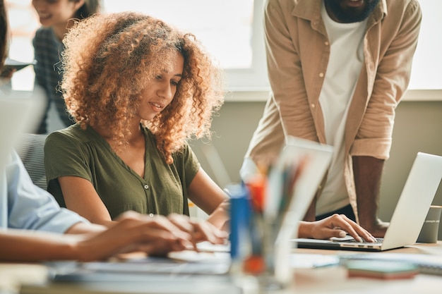 Foto impiegata femminile concentrata che si siede davanti al computer portatile