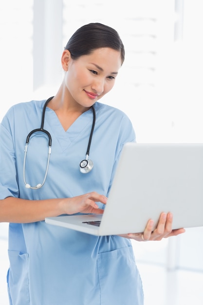 Concentrated female surgeon using a laptop