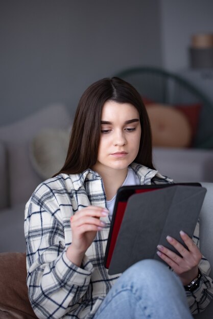 Concentrated girl doing video call on tablet using frontal camera for communicating